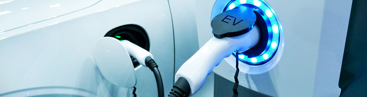 Close-up of an electric vehicle charging station featuring a plugged-in EV charger. 