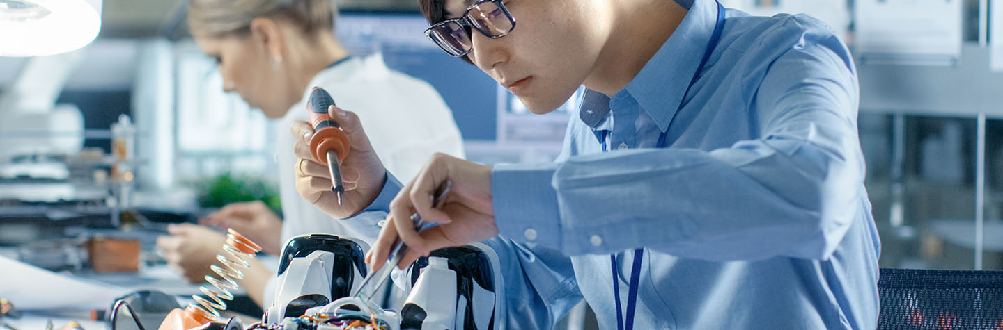 A professional in a blue shirt is assembling and testing robotic components in a modern office or laboratory setting.
