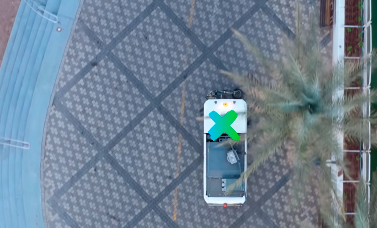 The image shows a small utility vehicle parked on a patterned pavement, captured from an overhead perspective..
