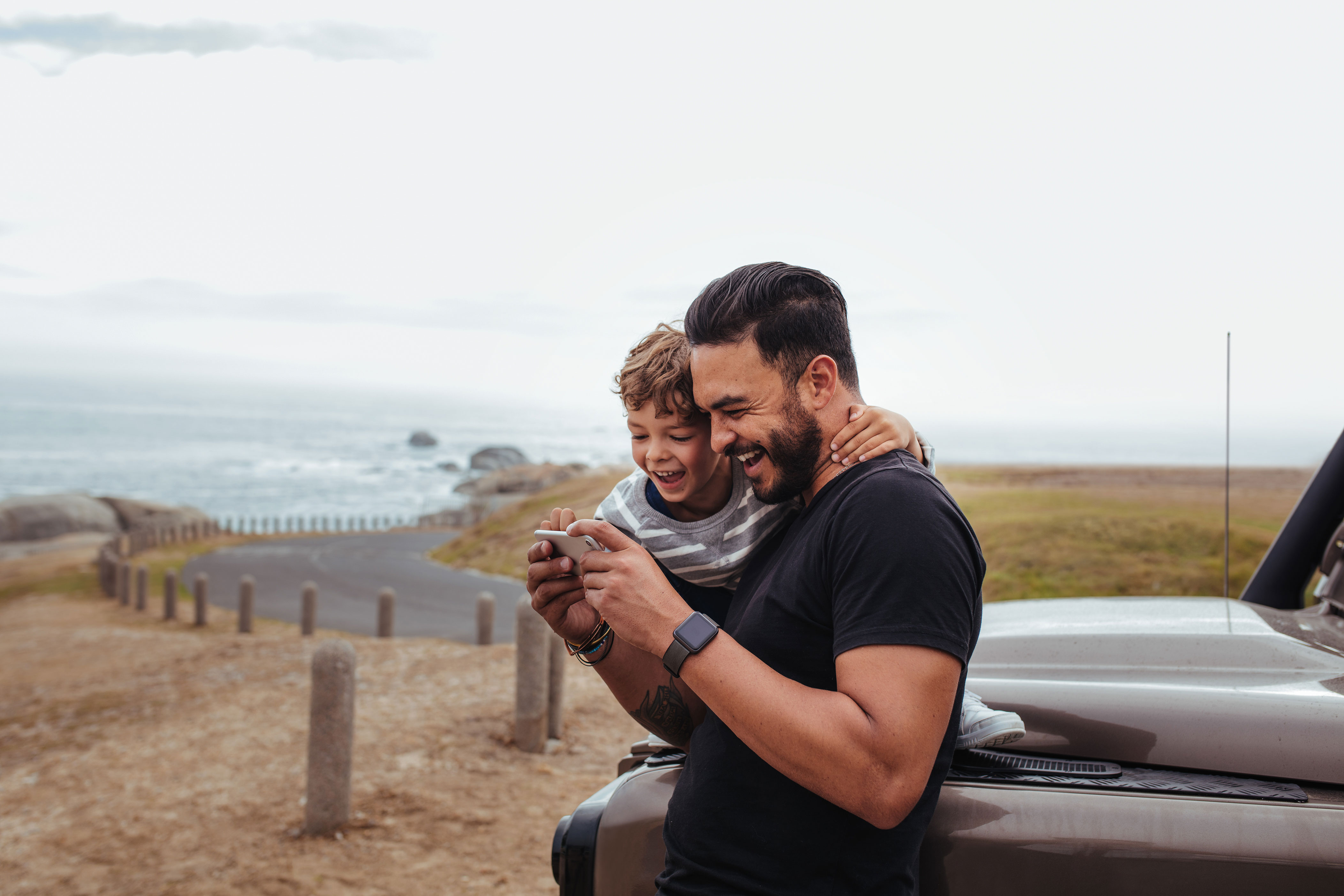 Man_Holding_Child_on_Phone_Near_Beach